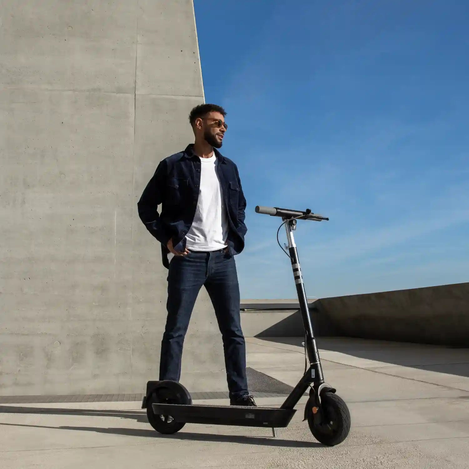 OKAI NEON Pro commuter scooter beside a rider in a modern outdoor setting
